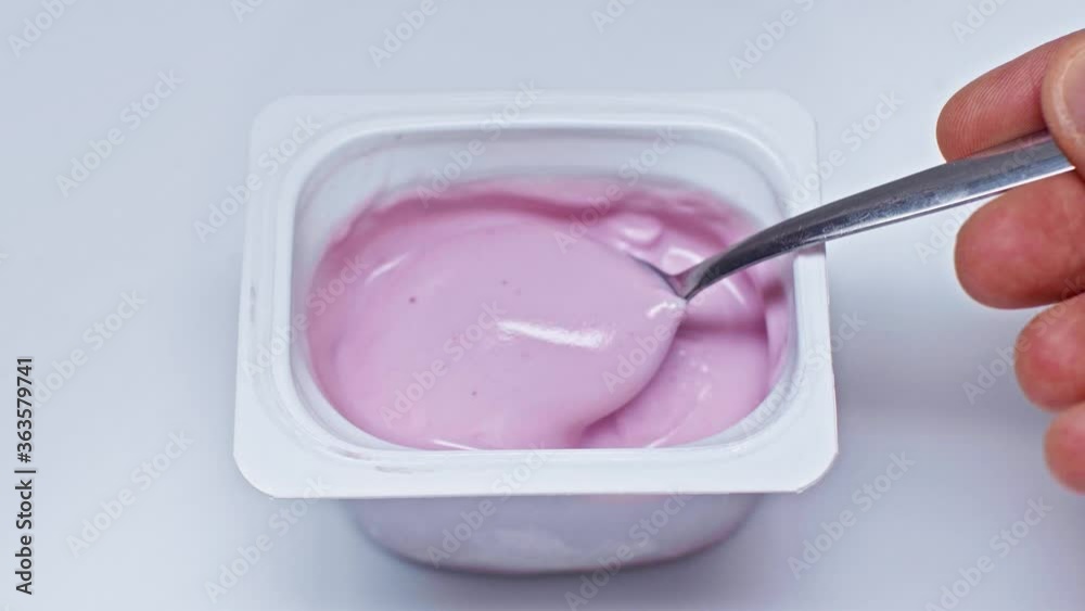 cropped view of man holding spoon near container with yogurt on white cropped view of man holding spoon near container with yogurt on white