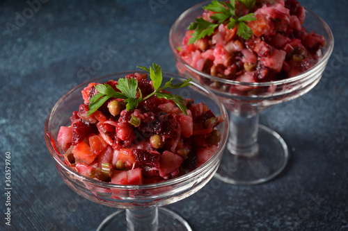 Vinegret or vinaigrette. Traditional Russian red salad with cooked and pickled vegetables, peas, beetroot, in two glass bowls on grey background.
 Vegan healthy dietary food