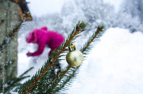 Little girl make a snowman behind the decorated fir-tree branches outdoors