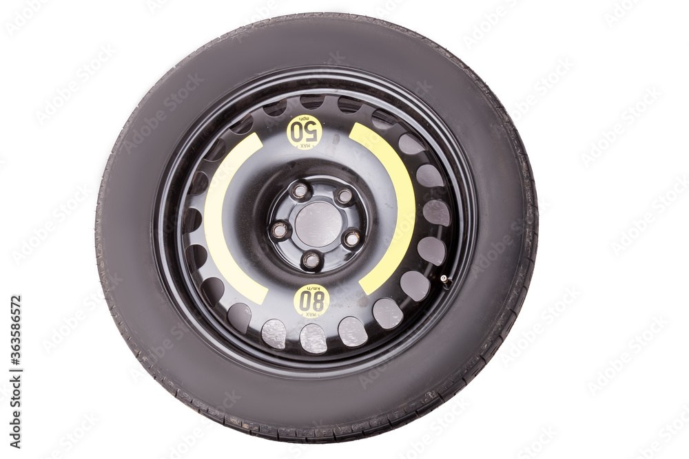 Fototapeta premium Full size black car spare tire with yellow marking and signs on a white background in a photo studio. Sale of spare summer tires or seasonal replacement in a car dismantling workshop.