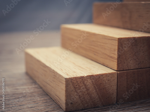 Arranging wood cube block stacking for top staircase shape on wooden table,Business concept and growth success process