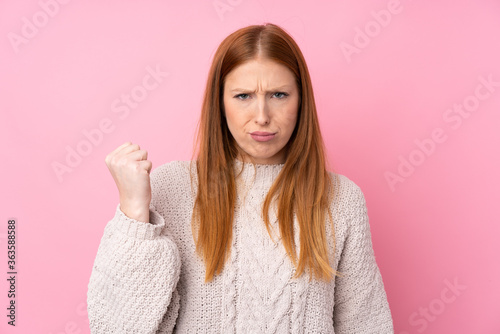 Young redhead woman over isolated pink background with angry gesture