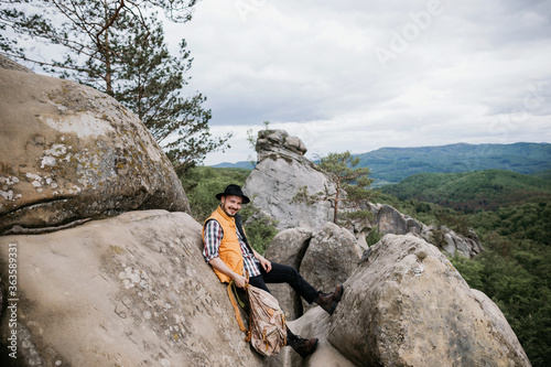 Hipster man in a hat with a backpack in the mountains