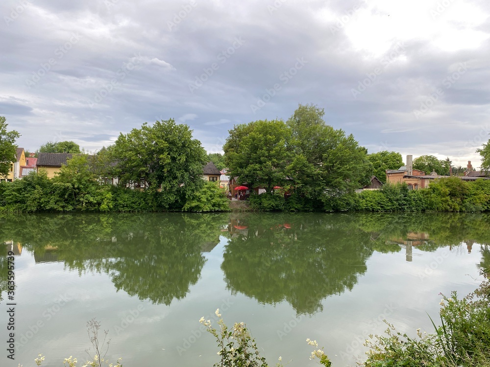 Fototapeta premium Neckar in Rottenburg im Sommer, bei bewegten Himmel. Biergarten, Bäume, Haus, auf der anderen Uferseite