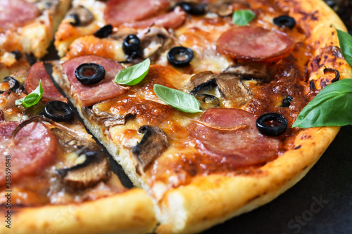 Pizza slices with mushrooms and olives on a black background.