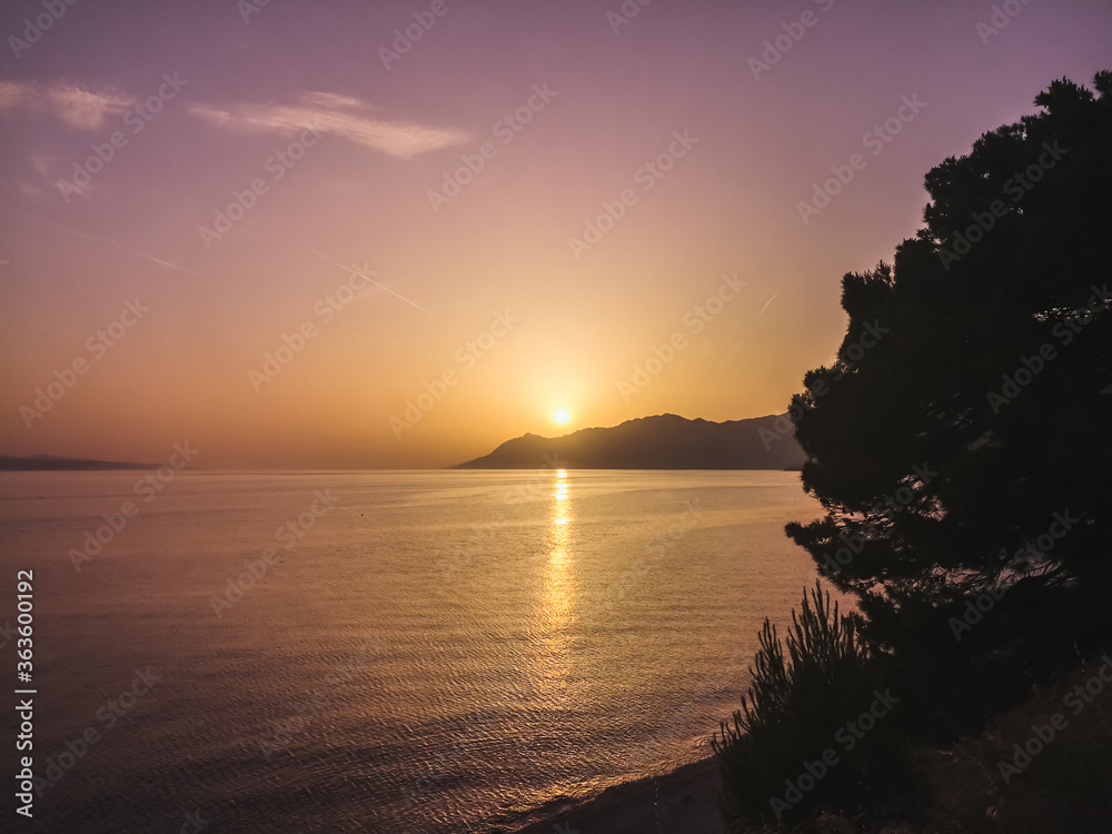 Scenic landscape with sunset over the sea, mountains on sunset sky background