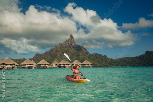 Woman paddling a kayak by the tropical beach.