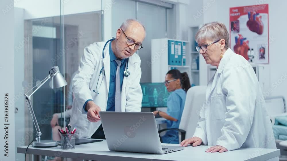 Elderly experienced doctors consulting each other in modern private clinic with glass walls. Senior authentic doctors in modern private hospital clinic room healthcare system medicine and treatment Elderly experienced doctors consulting each other in modern private clinic with glass walls. Senior authentic doctors in modern private hospital clinic room healthcare system medicine and treatment