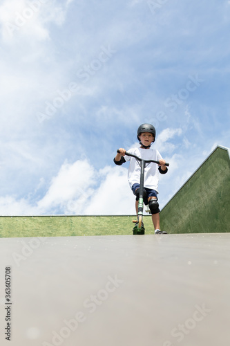 Obraz na płótnie A cute little boy rides a scooter in a skatepark. w salonie