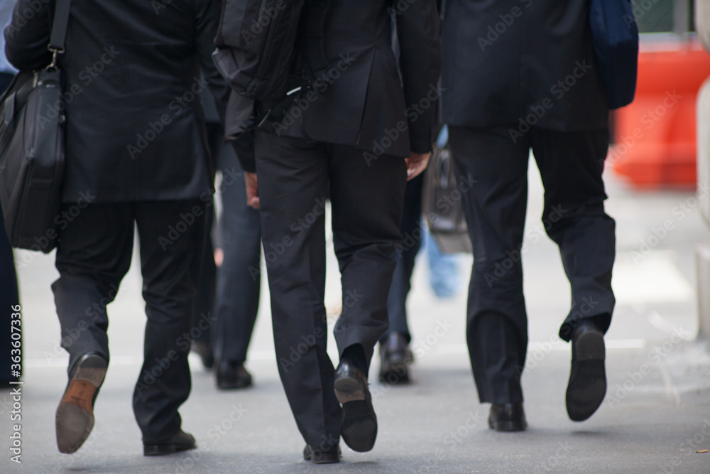 View from back of businessmen wearing suits walking on sidewalk