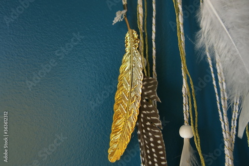 plume dorée en or acrochée avec des fils