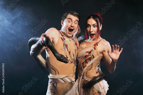 Beautiful man and woman Adam and Eve  posing with nature snake on a black background