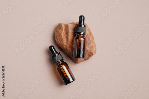 Amber glass eye dropper bottles mockups without labels on stone. Top view. Luxury beauty product packaging design