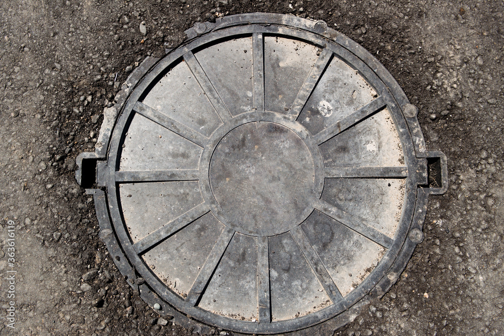 Grunge manhole. Plastic manhole, manhole cover on asphalt street. Manhole cover.