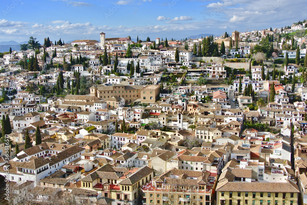 Panoramic view of the old part of Granada, Andalusia, Spain. White cozy houses and narrow streets on the hill against the blue sky