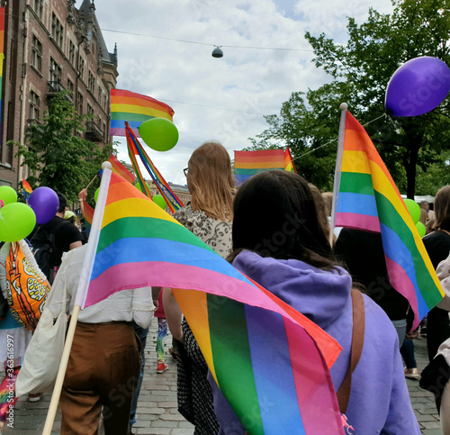 Big crowd marching on the streets to support inclusion and diversity during Helsinki Pride parade in 2019. Many are carrying rainbow flags.