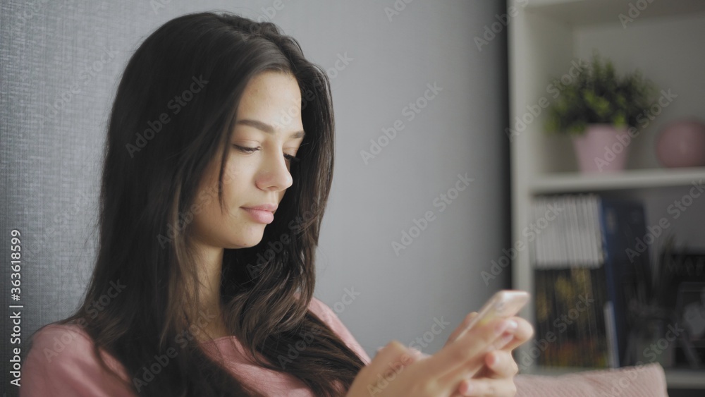 Woman sitting on a couch using her mobile phone to text a friend. Woman sitting on a couch using her mobile phone to text a friend.