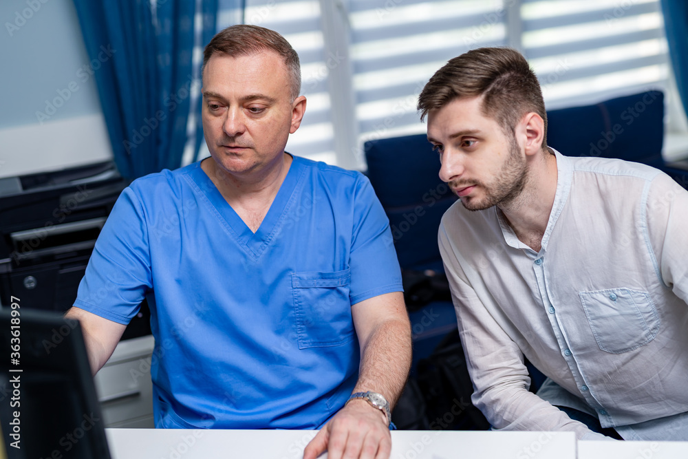 Consultation at doctor`s cabinet. Doctor and patient. Showing results on computer. Consultation at doctor`s cabinet. Doctor and patient. Showing results on computer.