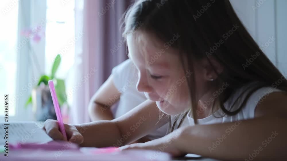In elementary school: portrait of a cute girl writes in an exercise book, smiles. In elementary school: portrait of a cute girl writes in an exercise book, smiles.