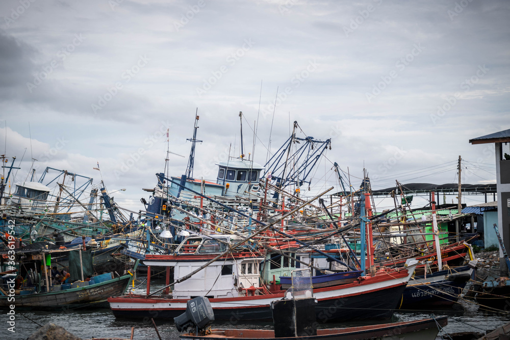 Chon buri,THAILAND-JULY 9,2020 : Fishing boat and fisherma in Thailand at Laemchabang Port in Thailand. Wooden boats. Old boat moored.Overcast sky.