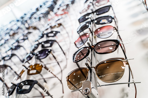 Row of glasses at an opticians. Eyeglasses shop. Stand with glasses in the store of optics. Raw of fashion elegance sunglasses in the store.