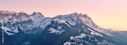 Beautiful scenery of a range of high rocky mountains covered with snow at sunset