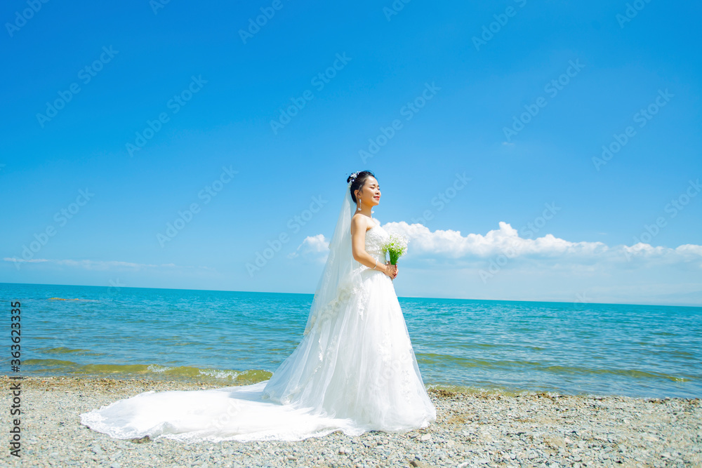 A girl in a wedding dress is modeling by the seaside lake. A girl in a wedding dress is modeling by the seaside lake.