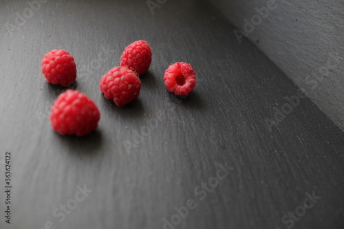 food background red raspberries are scattered lying on a gray stone black background there is a place to insert text photo