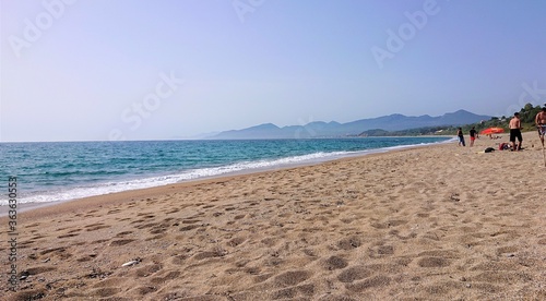 People enjoying a long stretch of sandy beach in Greece
