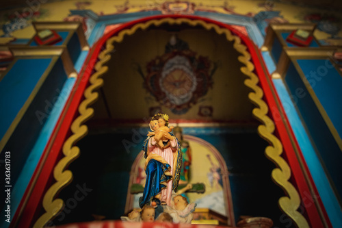 Saint with baby Jesus on his lap in colorful temple.