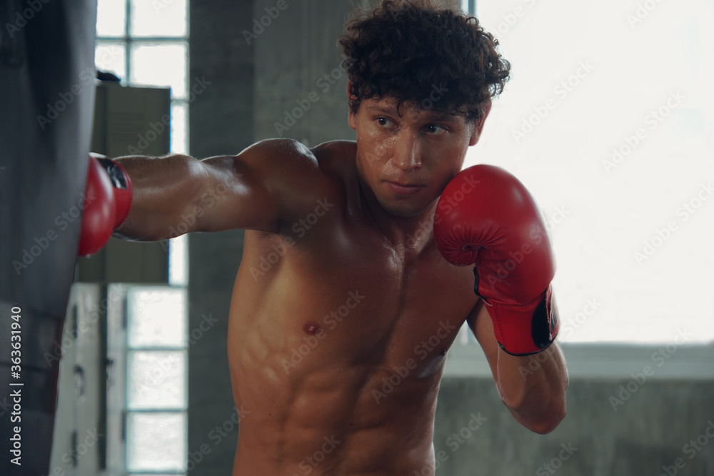 Young Caucasian muscular man making a hard punch on a punching bag with red Boxing Gloves. Handsome male Boxer Training Young Caucasian muscular man making a hard punch on a punching bag with red Boxing Gloves. Handsome male Boxer Training