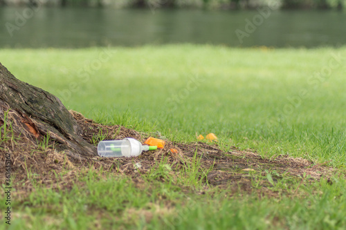 baby bottle lying on green grass. Environmental pollution concept