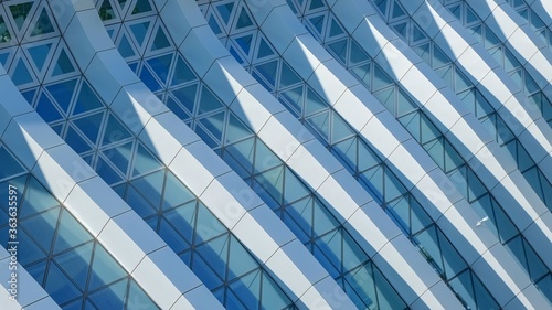 Modern architecture. Abstract pattern of shadows and light on curved diagonal lines of contemporary facade.Fragment of the facade of glass building.