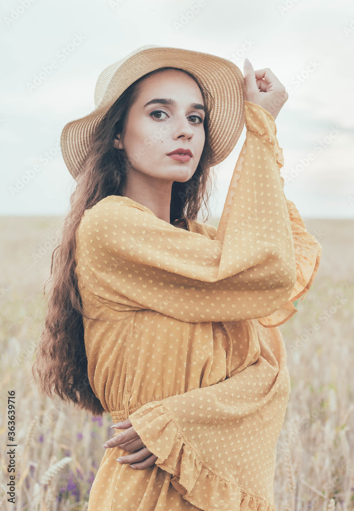 Φωτογραφία Portrait of a girl of model appearance on the field in a hat and dress