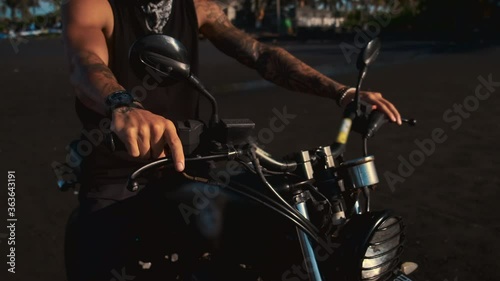biker on motorcycle on sandy beach, closeup