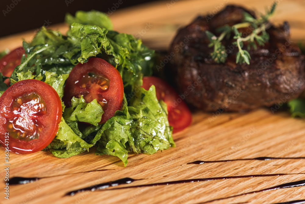 Healthy lean steak with medium-grilled beef with fried potatoes and green salad in a country pub or tavern, wooden tray. Close up view. For the menu 