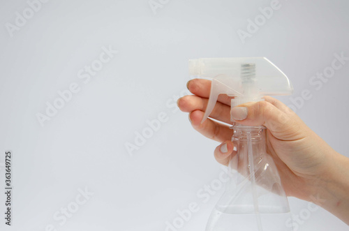 Female hand holding a hand sanitizer near the spray bottle on a white background