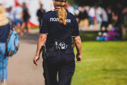 Russian female police squad formation back view with "Police" emblem on uniform maintain public order after football game with football fans crowd in the background