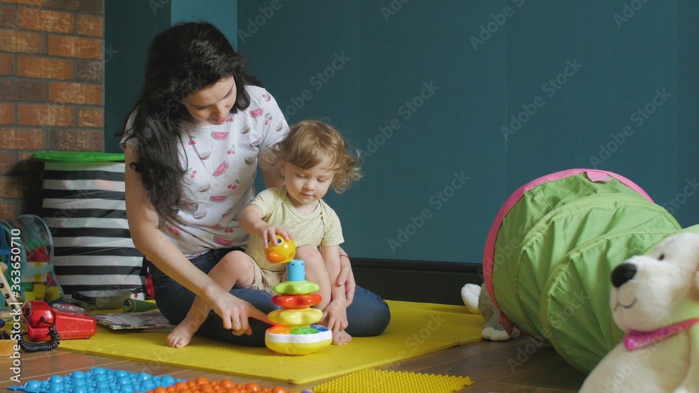 Fototapeta premium Mother and daughter playing with children's pyramid
