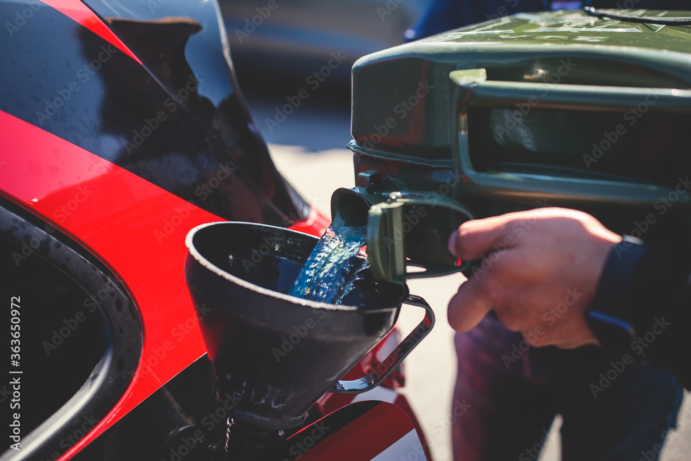 Obraz premium Process of refueling the sportcar tank with gasoline from canister during test-drive racing competition event