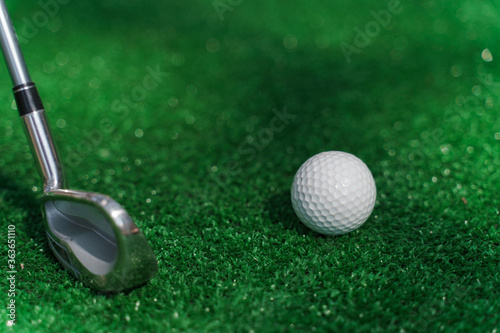 Close-up niblick and white ball for golf on the green grass. Empty right side for text of advert for golf clubs. Playing in golf