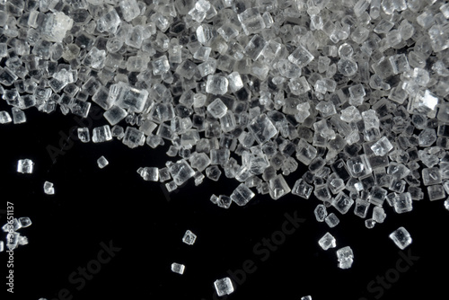 Fullscreen macro closeup with shallow depth of field of small sugar grains on a black background. Texture. Graphic design. photo