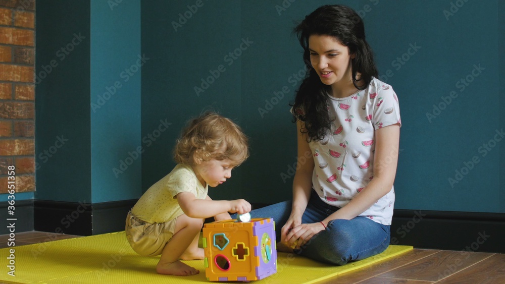 Fototapeta premium Little girl is playing with Activity Sorter Cube