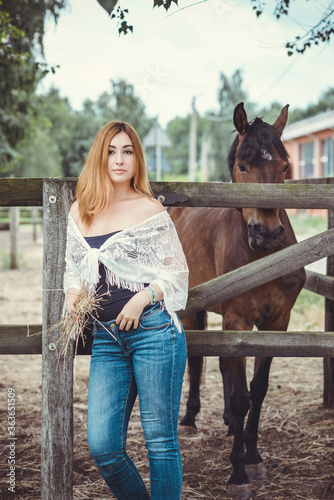 Woman in fashionable Bohemian casual style with horses on a farm, pets animals in village at rancho. Horses are human friends