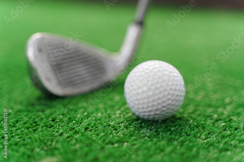 Close-up playing in mini-golf on the green grass using niblick. Player hits white ball. Golf sport game. Advert for golf club