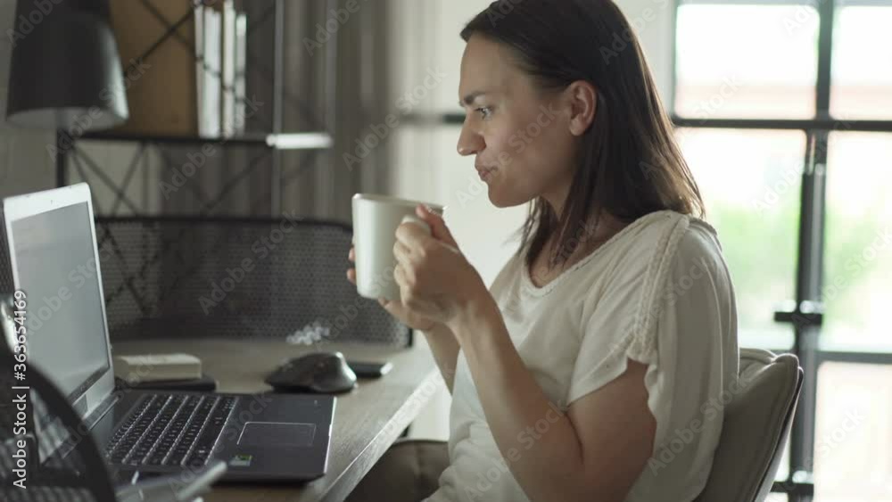 Beautiful woman drinking coffee and working on her laptop Beautiful woman drinking coffee and working on her laptop