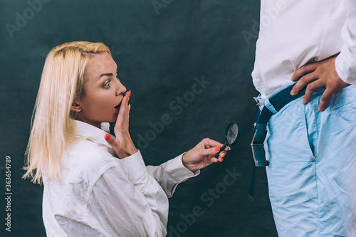 Fotografie A woman with a magnifying glass in her hands checks male dignity with a guy
