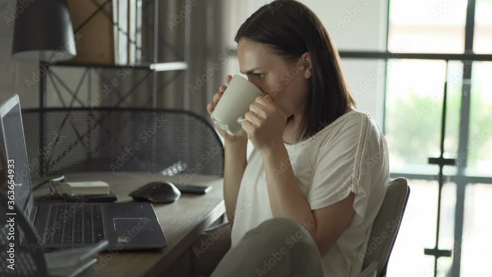 Beautiful woman drinking coffee and working on her laptop Beautiful woman drinking coffee and working on her laptop