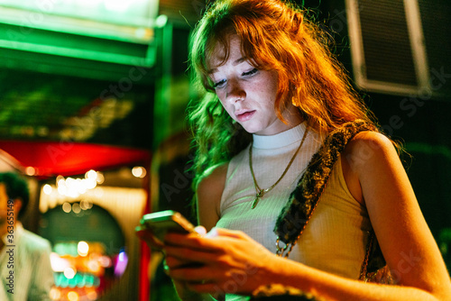 Ginger woman is using her smartphone on the street.
