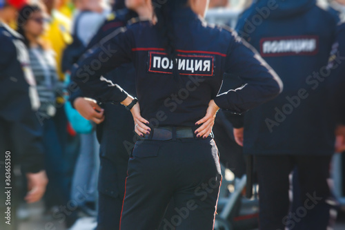 Russian police squad formation back view with "Police" emblem on uniform maintain public order after football game with football fans crowd in the background